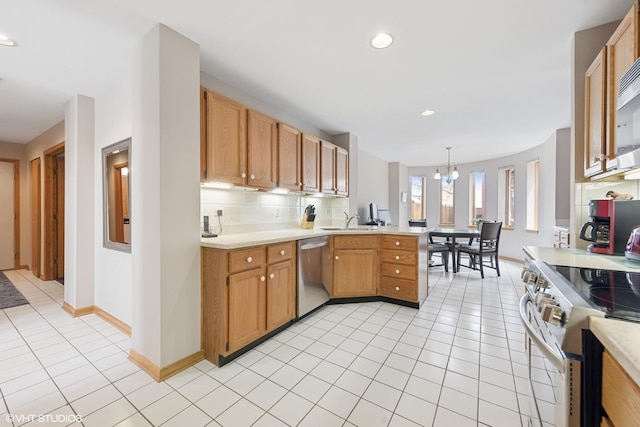kitchen featuring a peninsula, light tile patterned flooring, light countertops, a sink, and appliances with stainless steel finishes