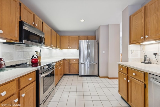 kitchen with decorative backsplash, baseboards, light countertops, appliances with stainless steel finishes, and light tile patterned floors