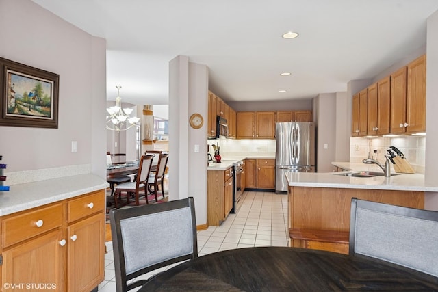 kitchen with backsplash, light tile patterned floors, light countertops, a sink, and stainless steel appliances