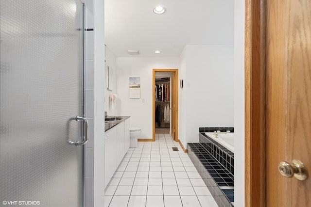 full bathroom featuring tile patterned flooring, a shower stall, vanity, a spacious closet, and tiled bath