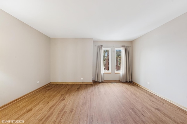 empty room featuring baseboards and light wood-style floors