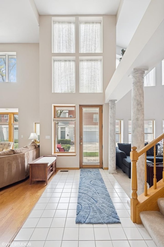 tiled entrance foyer featuring stairway, a high ceiling, and decorative columns