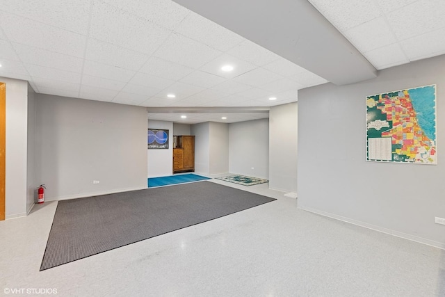 finished basement featuring baseboards, a drop ceiling, and recessed lighting
