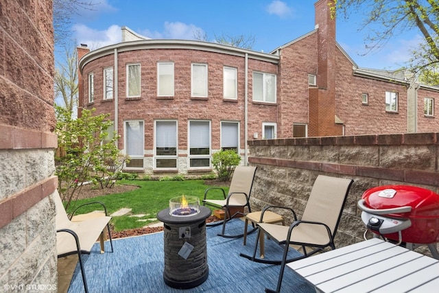 rear view of house with an outdoor fire pit, a patio area, and a chimney