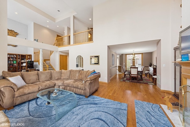 living area featuring baseboards, a towering ceiling, wood finished floors, and a chandelier