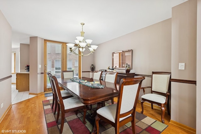 dining area with light wood-type flooring, baseboards, and a chandelier