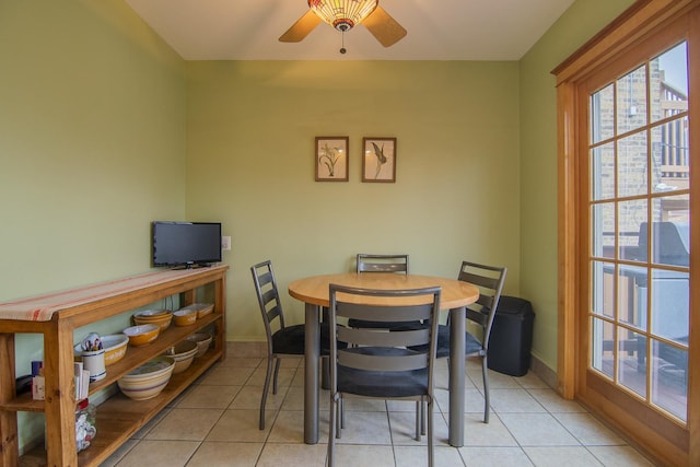 dining space with a ceiling fan, baseboards, and light tile patterned floors
