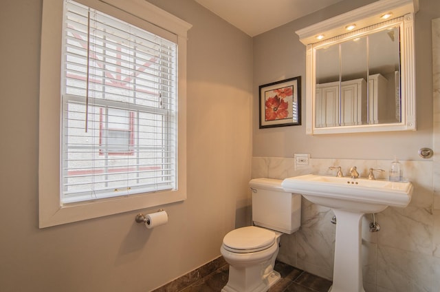 half bath featuring toilet, tile patterned flooring, and tile walls