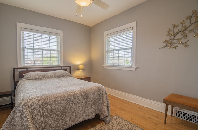 bedroom featuring baseboards, multiple windows, and wood finished floors