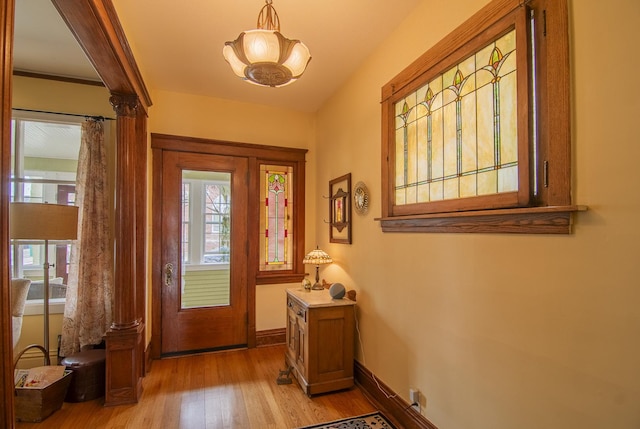 entryway featuring light wood finished floors, baseboards, and a notable chandelier