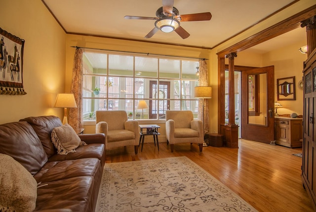 living area with wood finished floors, ornamental molding, and ceiling fan