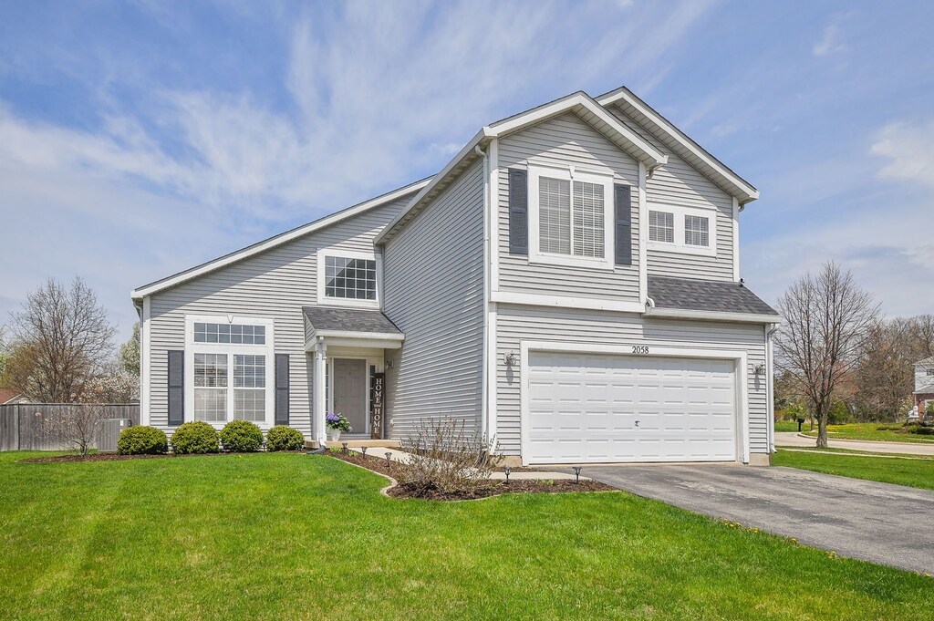2058 Westbury Ln, Aurora, IL 60502 - traditional-style house with fence, cooling unit, a garage, driveway, and a front lawn
