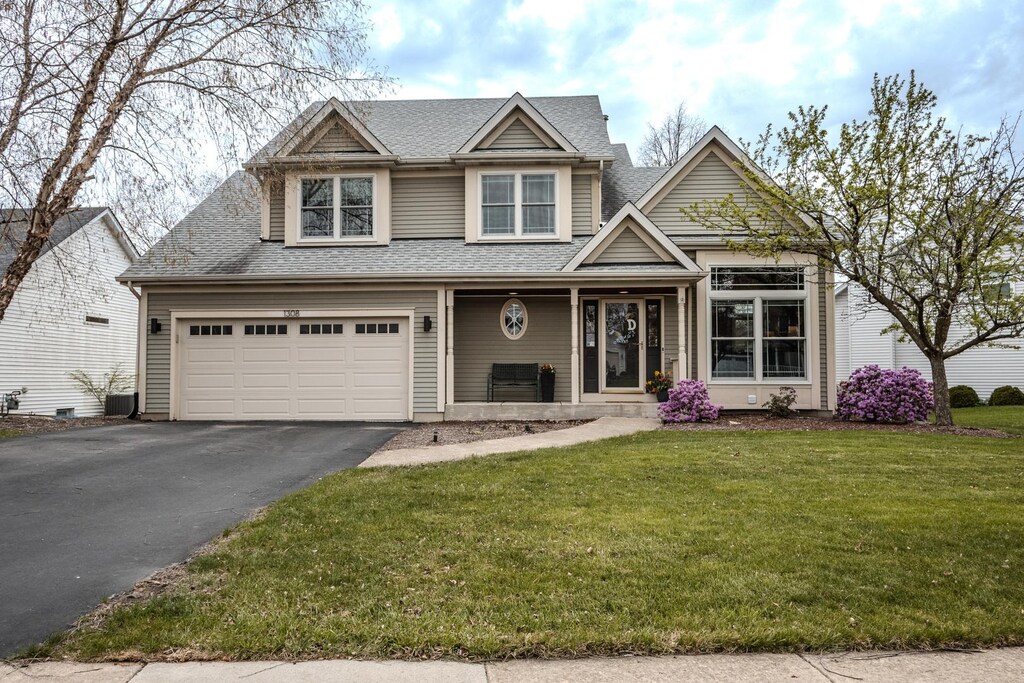 1308 Meadow Ln, North Aurora, IL 60542 - view of front of property featuring central AC, a front lawn, aphalt driveway, covered porch, and roof with shingles