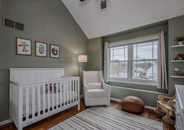 bedroom with a nursery area, vaulted ceiling, visible vents, and wood finished floors