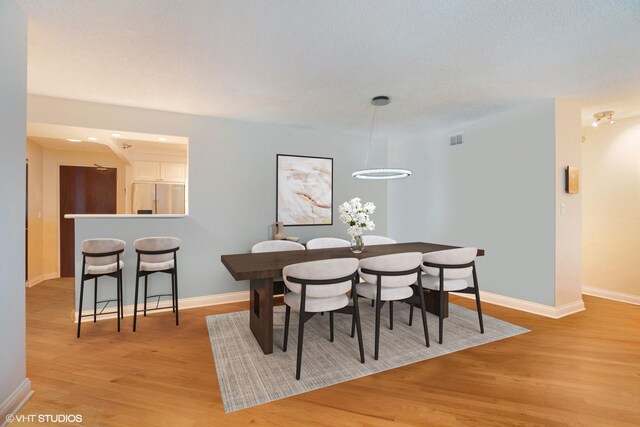 dining space with light wood-style flooring, visible vents, and baseboards