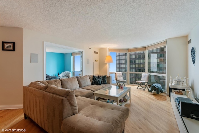 living area featuring floor to ceiling windows, a textured ceiling, and light wood-style flooring