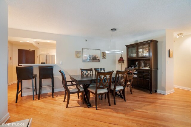 dining space with baseboards and light wood finished floors