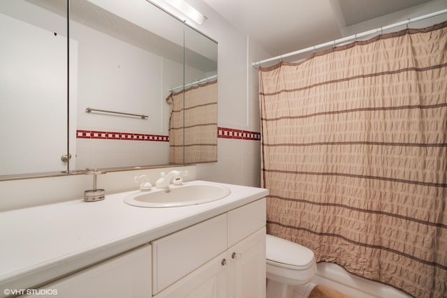 bathroom with tile walls, shower / bath combo with shower curtain, vanity, and toilet