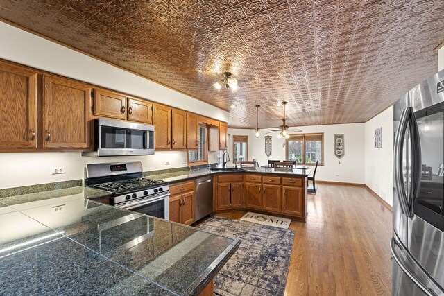 kitchen with an ornate ceiling, tile counters, a sink, stainless steel appliances, and a peninsula
