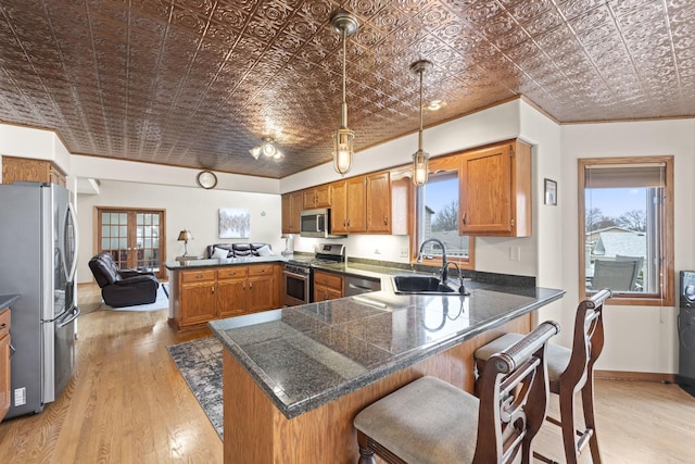 kitchen featuring an ornate ceiling, a sink, brown cabinetry, stainless steel appliances, and a peninsula