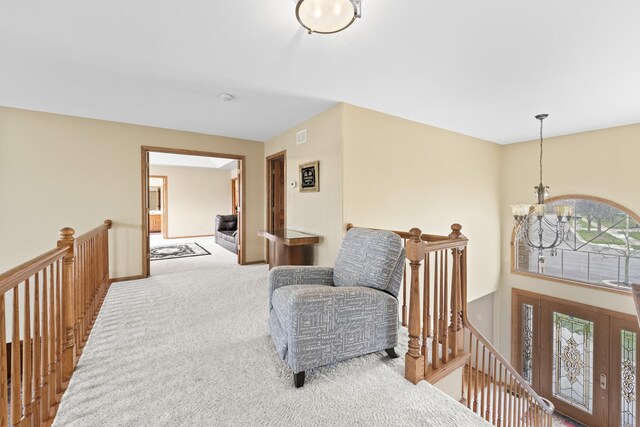 living area with an inviting chandelier, visible vents, carpet floors, and an upstairs landing