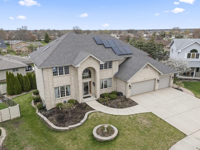traditional home featuring concrete driveway, roof with shingles, a front yard, and a garage