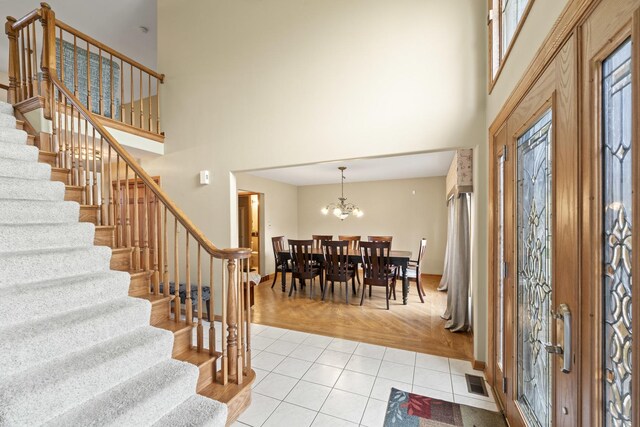 foyer with a high ceiling, stairs, visible vents, and baseboards