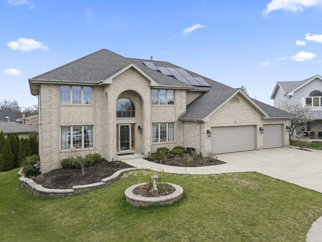 view of front facade featuring brick siding, solar panels, an attached garage, and a front yard
