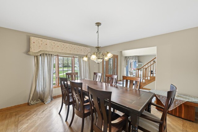 dining area featuring light wood finished floors, baseboards, a chandelier, and stairway