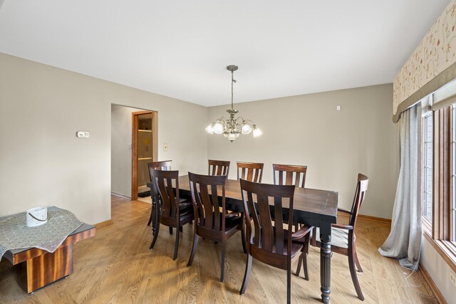 dining space featuring baseboards, an inviting chandelier, and light wood-style flooring