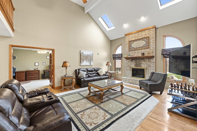living area featuring wood finished floors, beamed ceiling, a skylight, a brick fireplace, and high vaulted ceiling