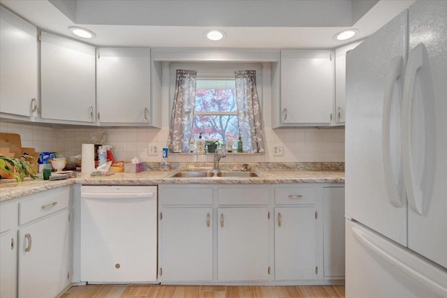 kitchen with a sink, light countertops, decorative backsplash, and white appliances