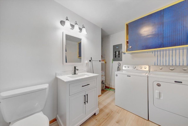 interior space with laundry area, light wood-type flooring, washer and clothes dryer, electric panel, and a sink