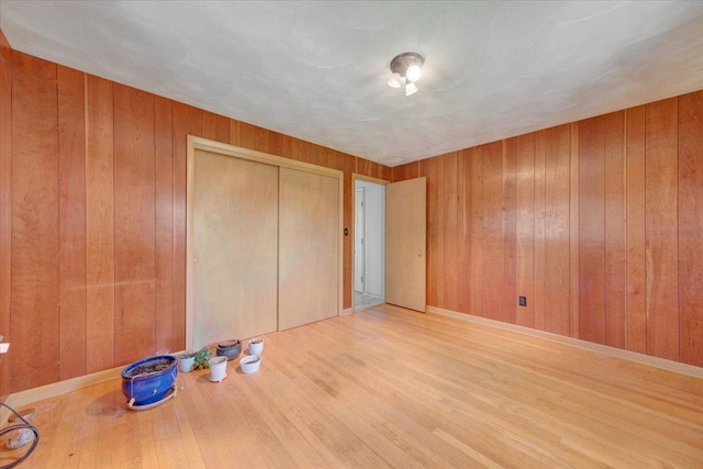 unfurnished bedroom featuring wooden walls, a closet, and wood finished floors