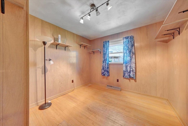 spare room with rail lighting, visible vents, wood walls, and wood finished floors