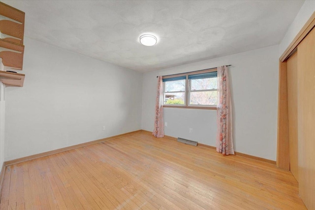 unfurnished bedroom with baseboards, a closet, light wood-type flooring, and visible vents