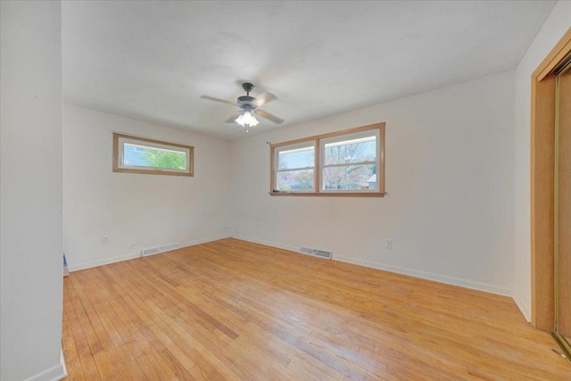 unfurnished room with visible vents, a ceiling fan, light wood-style floors, and baseboards