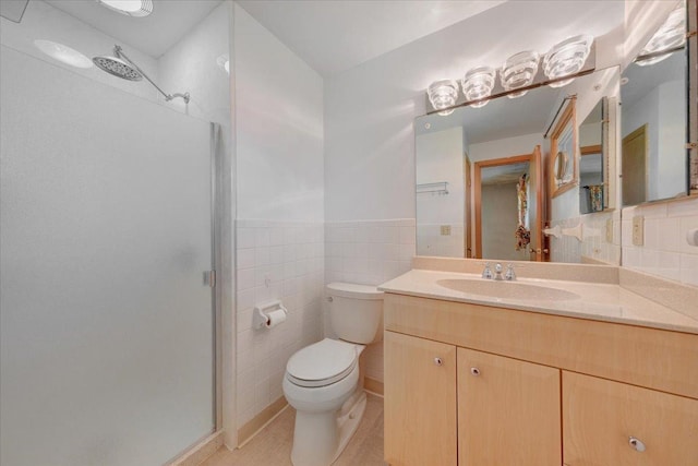 full bathroom with tile walls, a shower stall, vanity, a wainscoted wall, and toilet