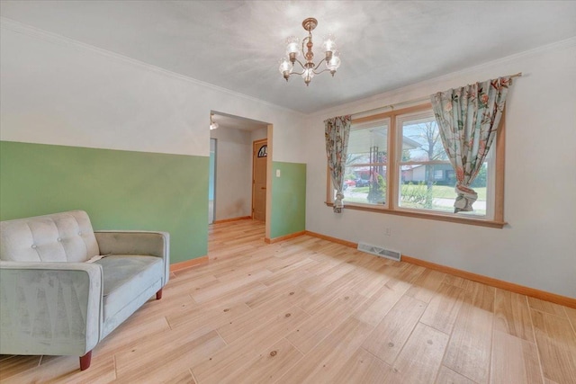 living area with baseboards, an inviting chandelier, ornamental molding, and visible vents