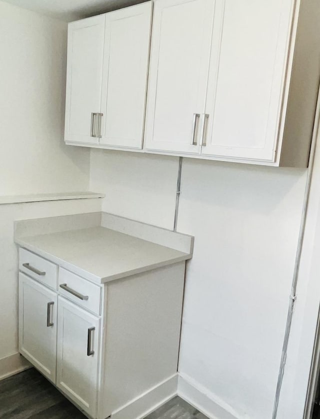 laundry room with baseboards and dark wood finished floors