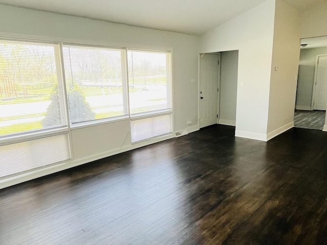 empty room with baseboards, dark wood finished floors, and lofted ceiling
