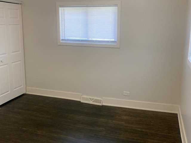 unfurnished room with visible vents, baseboards, and dark wood-type flooring