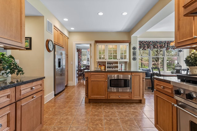915 W Clark St, Champaign, IL 61821 - kitchen featuring appliances with stainless steel finishes, light tile patterned flooring, recessed lighting, dark stone counters, and baseboards