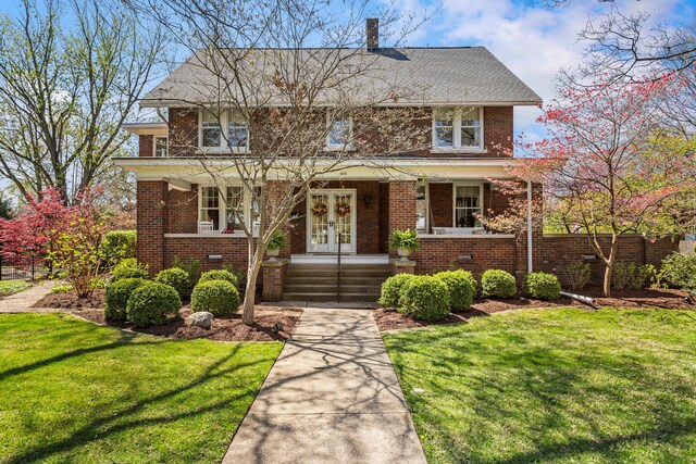 915 W Clark St, Champaign, IL 61821 - traditional style home with covered porch, brick siding, a front yard, and french doors