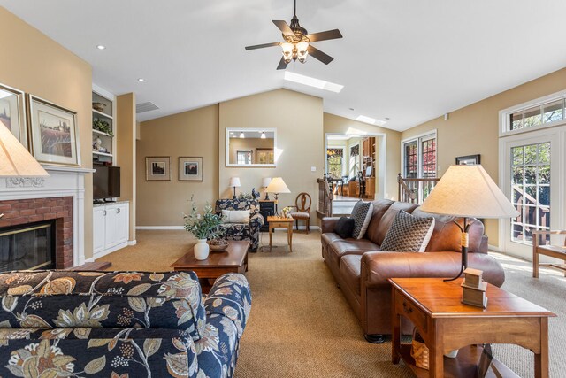 915 W Clark St, Champaign, IL 61821 - living room with light colored carpet, a ceiling fan, vaulted ceiling, a fireplace, and a skylight