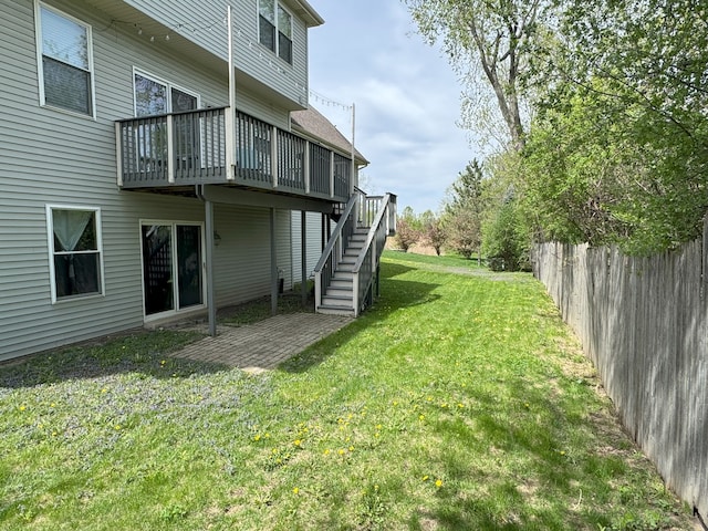 view of yard with fence, a wooden deck, and stairs