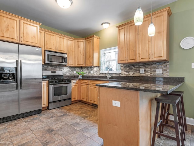 kitchen with stone finish flooring, a peninsula, appliances with stainless steel finishes, and decorative backsplash