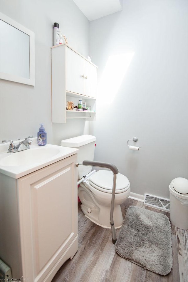 bathroom with visible vents, wood finished floors, toilet, and vanity