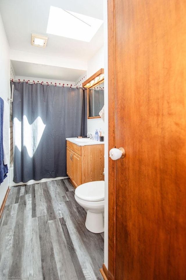 bathroom featuring toilet, vanity, a shower with curtain, and wood finished floors