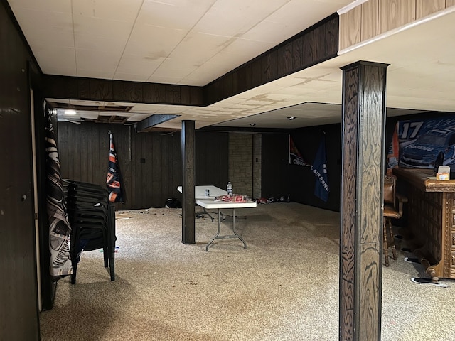 finished below grade area featuring wooden walls and carpet flooring